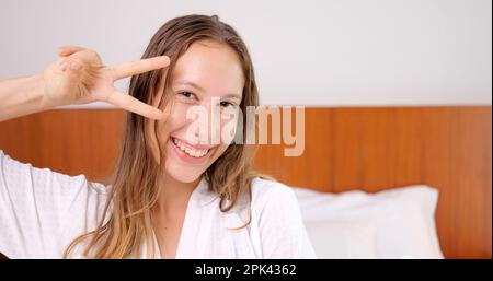 Portrait d'une jeune femme souriante en peignoir blanc regardant l'appareil photo Banque D'Images