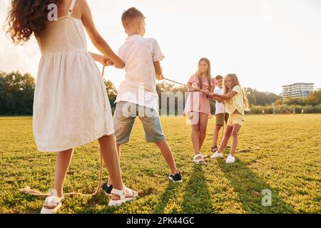 Jouer au remorqueur de la guerre. Groupe d'enfants heureux est à l'extérieur sur le terrain sportif en journée Banque D'Images