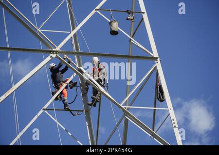 Les électriciens travaillent en hauteur pour démonter un pylône haute tension pour le remplacement. Milan, Italie - avril 2023 Banque D'Images