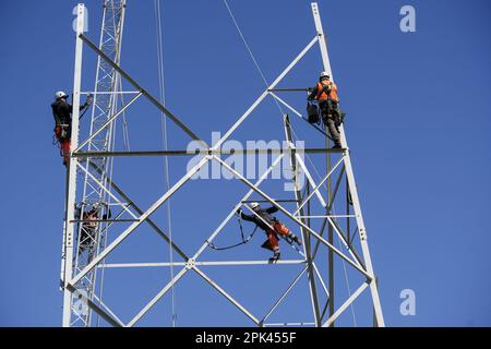 Les électriciens travaillent en hauteur pour démonter un pylône haute tension pour le remplacement. Milan, Italie - avril 2023 Banque D'Images