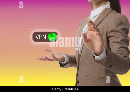 Femme et activé bouton VPN sur fond couleur, gros plan Banque D'Images