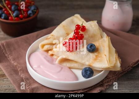 Crêpes délicieuses au yaourt naturel, bleuets et raisins rouges sur table en bois Banque D'Images