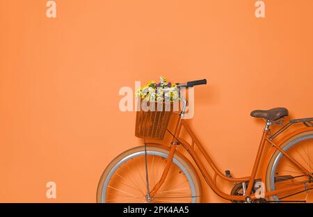 Vélo rétro avec panier en osier sur fond orange Banque D'Images