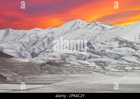 Vue magique du coucher de soleil sur un petit village de montagne avec de la neige en Ombrie Italie Banque D'Images
