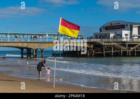 Bournemouth, Royaume-Uni - 2 avril 2023 : un drapeau de sauveteur RNLI sur la plage de Bournemouth en face de la jetée. Banque D'Images