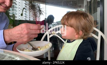 Grand-père nourrissant tout-petit petit petit-fils bébé Banque D'Images