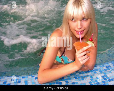 jeune belle femme se détendant dans la piscine avec un cocktail Banque D'Images