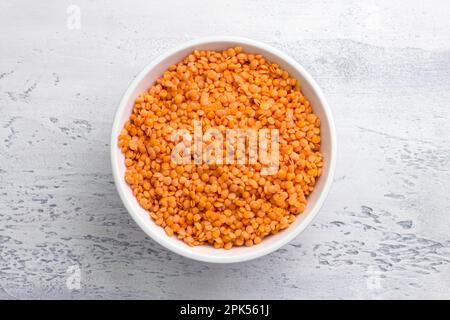 Lentilles crues trempées dans un bol blanc sur fond gris clair, vue du dessus. Concept d'alimentation saine Banque D'Images