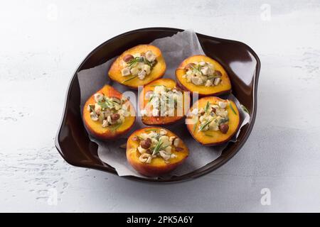 Pêches farcies au fromage bleu aux noix et au romarin dans un plat de cuisson sur fond gris clair, vue du dessus. Cuisine délicieux dessert gastronomique Banque D'Images