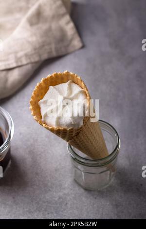 Cornet de gaufres avec glace à la vanille dans un pot de café sur fond gris, vue du dessus Banque D'Images