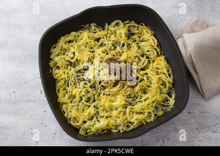 Poêle antiadhésive avec oignons frits et épices : cumin et poivre noir, vue de dessus. Cuisine du plat traditionnel du Moyen-Orient Mujadara Banque D'Images