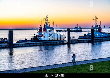 La jetée de remorqueurs, remorqueurs de port en attente de la prochaine affectation, au Nouveau port, coucher de soleil sur l'estuaire de Weser avec à Bremerhaven, Brême, Allemagne Banque D'Images