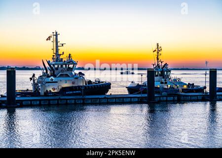 La jetée de remorqueurs, remorqueurs de port en attente de la prochaine affectation, au Nouveau port, coucher de soleil sur l'estuaire de Weser avec à Bremerhaven, Brême, Allemagne Banque D'Images