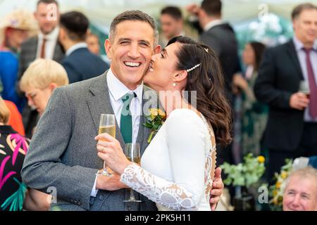 Mariée/femme embrassant marié/mari, souriant, marié regardant l'appareil photo Banque D'Images