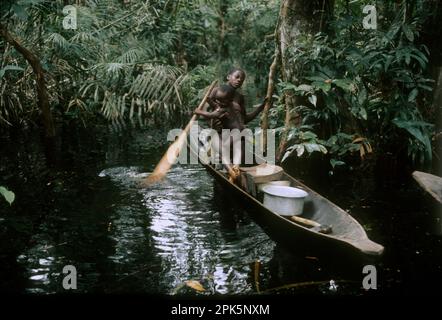 Afrique, République démocratique du Congo, région des îles de la rivière Ngiri, groupe ethnique Libinza : fille avec bébé apprenant à pagayer en canoë dans la forêt marécageuse. Banque D'Images