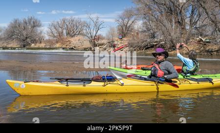 Evans, CO, Etats-Unis - 1 avril 2023: Les kayakistes se reposent et prennent des photos sur un banc de sable après le portage du barrage au cours d'un voyage de pagayage au printemps sur le Sud Banque D'Images