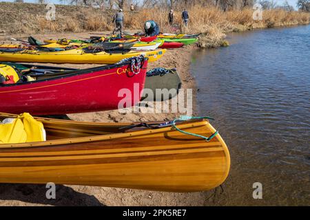 Evans, CO, Etats-Unis - 1 avril 2023 : canoës et kayaks alignés sur une plage avant le printemps de pagayer sur la rivière Platte Sud. Banque D'Images