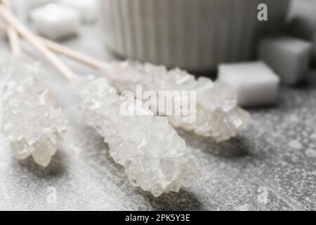 Bâtons avec cristaux de sucre sur table gris clair, gros plan. Bonbons savoureux Banque D'Images