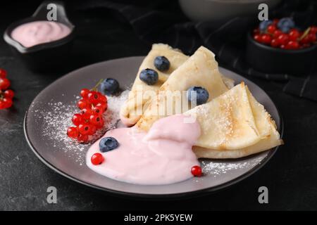 Crêpes délicieuses au yaourt naturel, bleuets et raisins de Corinthe rouges sur table gris foncé Banque D'Images