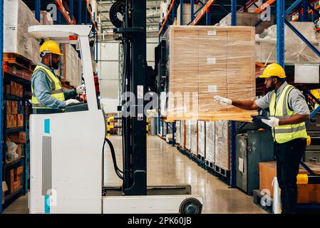 Un employé d'entrepôt professionnel déplace les boîtes en carton par le chargeur de chariot élévateur Banque D'Images