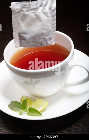 Gros plan de la mise du sachet de thé dans la tasse de thé au citron Banque D'Images