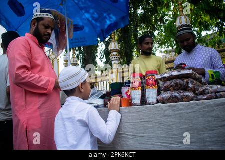 Le père musulman indien achète le chapeau à son fils avant d'exécuter la prière du deuxième vendredi dans le mois Saint du Ramadan dans une mosquée à Guwahati, en Inde Banque D'Images