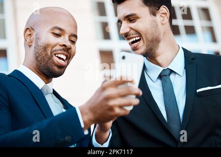 Les hommes d'affaires ont aussi tendance à bander. de jeunes hommes d'affaires de handsome utilisant un téléphone portable ensemble à l'extérieur. Banque D'Images