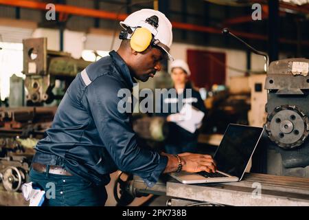 Technicien spécialisé avec un uniforme de sécurité utilisant une machine de contrôle d'ordinateur portable Banque D'Images