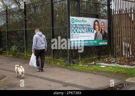 Un homme passe devant une affiche électorale montrant le conseiller de Sinn Fein Róis-Máire Donnelly , à l' ouest de Belfast , en Irlande du Nord . Banque D'Images