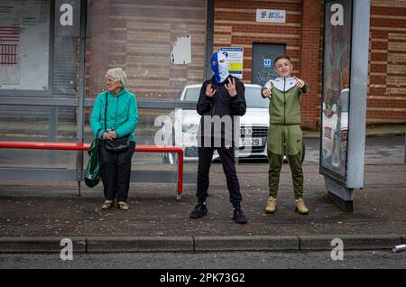 Un jeune garçon portant une balaclava pour cacher son visage à un arrêt de bus à Shankill Road, Belfast, County Antrim, Irlande du Nord, Royaume-Uni. Banque D'Images