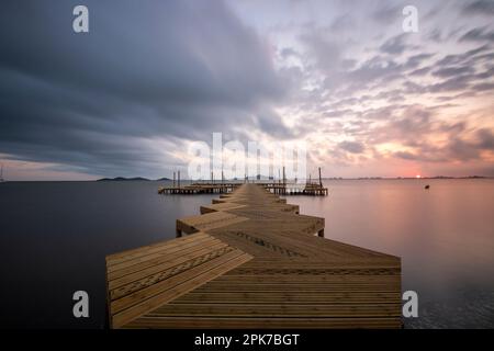 Jetée en bois sur la plage de Carmol dans la Mar Menor, au lever du soleil nuageux, à Cartagena, région de Murcie, Espagne Banque D'Images