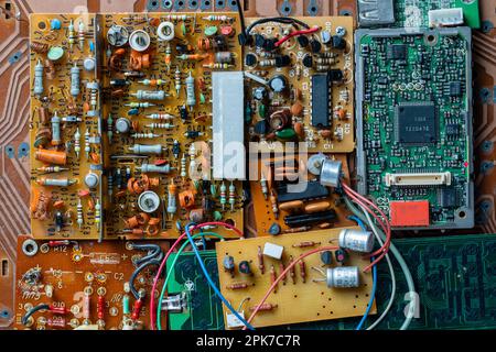 De nombreuses anciennes cartes de circuits imprimés avec des composants radio en arrière-plan. Cartes de circuit imprimé vintage avec traces de soudure, pièces et microcircuits, gros plan, à Banque D'Images