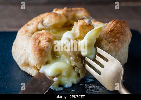 Camembert cuit dans une pâte feuilletée avec une fourchette et un couteau, gros plan Banque D'Images