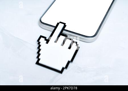 Le grand modèle de curseur à main pixélisé en plastique touche un écran vide d'un smartphone moderne. Concept de navigation et d'interaction avec les périphériques numériques. Banque D'Images