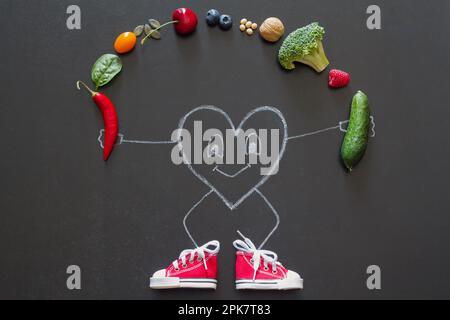 Coeur en toile chaussures sur le tableau noir jonglant fruits, drôle concept diète et le sport pour le coeur sain Banque D'Images