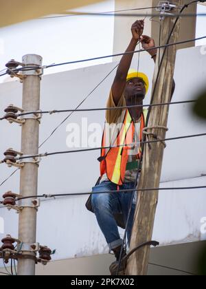 Dar es Salaam, Tanzanie - février 2021 : homme africain qui fait de l'électricité sur un poteau électrique. Afrique. Banque D'Images