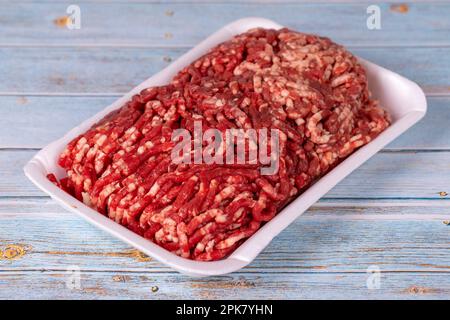 Bœuf haché cru dans un plateau en polystyrène blanc sur fond de bois. Bœuf haché frais sur fond de bois. Banque D'Images