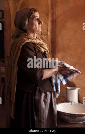 Femme en costume de renaissance paysanne lavant ses mains dans un bassin antique Banque D'Images
