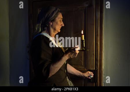 Femme d'une tenue médiévale debout à une porte avec un ancien porte-bougie Banque D'Images