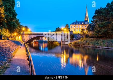 Les eaux tranquilles de la rivière Avon serpentent à travers la ville et l'église St John's s'élève de façon spectaculaire contre un ciel bleu à Bath, au Royaume-Uni Banque D'Images