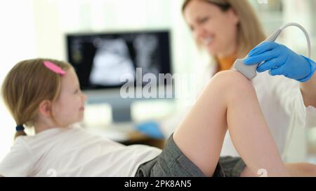 Médecin pédiatre effectuant un examen échographique de l'articulation du genou de l'enfant en clinique de proximité Banque D'Images