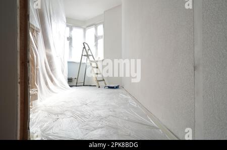 Intérieur d'un nouvel appartement sans finition dans les tons gris avec échelle en métal pliante. Concept de travaux de réparation et de finition. Banque D'Images