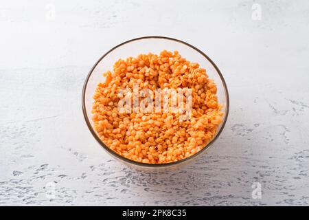 Lentilles crues trempées dans un bol blanc sur fond gris clair, vue du dessus. Concept d'alimentation saine Banque D'Images