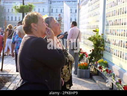 Les mères de vieilles femmes qui pleurent devant le mur du souvenir mettent des fleurs. Réunion consacrée à l'anniversaire de la bataille d'Ilovaisk (guerre à Donbass Banque D'Images