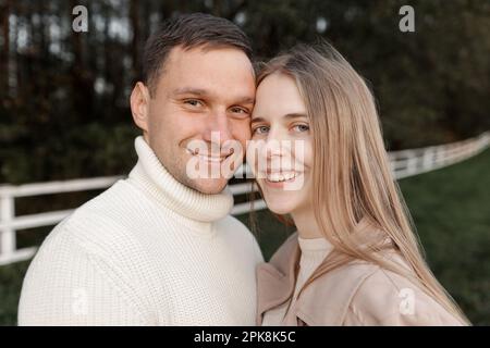 Jeune heureux romantique couple enceinte marche main à l'extérieur à l'automne chaud jour. Femme enceinte en robe tricotée et son beau homme s'attendait Banque D'Images
