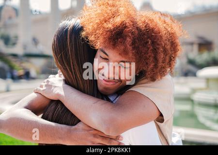 portrait en gros plan d'un couple joyeux et adolescent qui s'embrasse ensemble. Un jeune afro-américain avec des cheveux afro souriants et donnant un câlin affectueux à sa petite amie montrant de bons sentiments et de l'amour . Photo de haute qualité Banque D'Images
