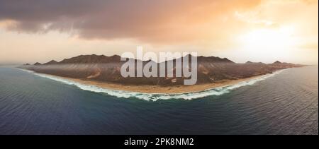 Vue d'en haut, vue panoramique sur la plage de Cofete entourée par la chaîne de montagnes du Parc naturel de Jandía pendant un beau coucher de soleil. Banque D'Images