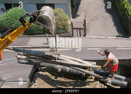 les anciens tuyaux déposés sont chargés par une pelle hydraulique sur un tombereau de tombereau pendant les travaux routiers Banque D'Images