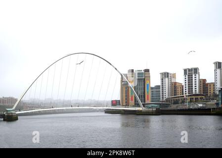 Newcastle upon Tyne, Tyne and Wear, Angleterre, Royaume-Uni. Gateshead Millennium Bridge(2001) de l'autre côté de la rivière Tyne, Gateshead sur la rive éloignée. Gris, jour de pluie Banque D'Images