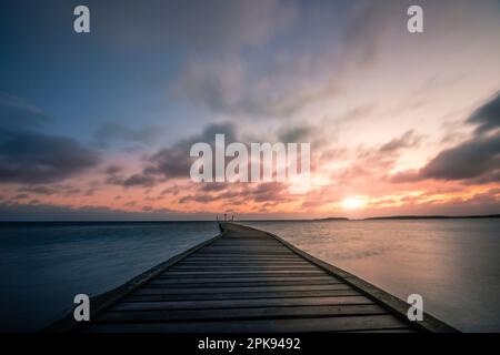 Suède, vue depuis la rive sur le lac, eau calme, lever du soleil avec réflexion dans l'eau Banque D'Images